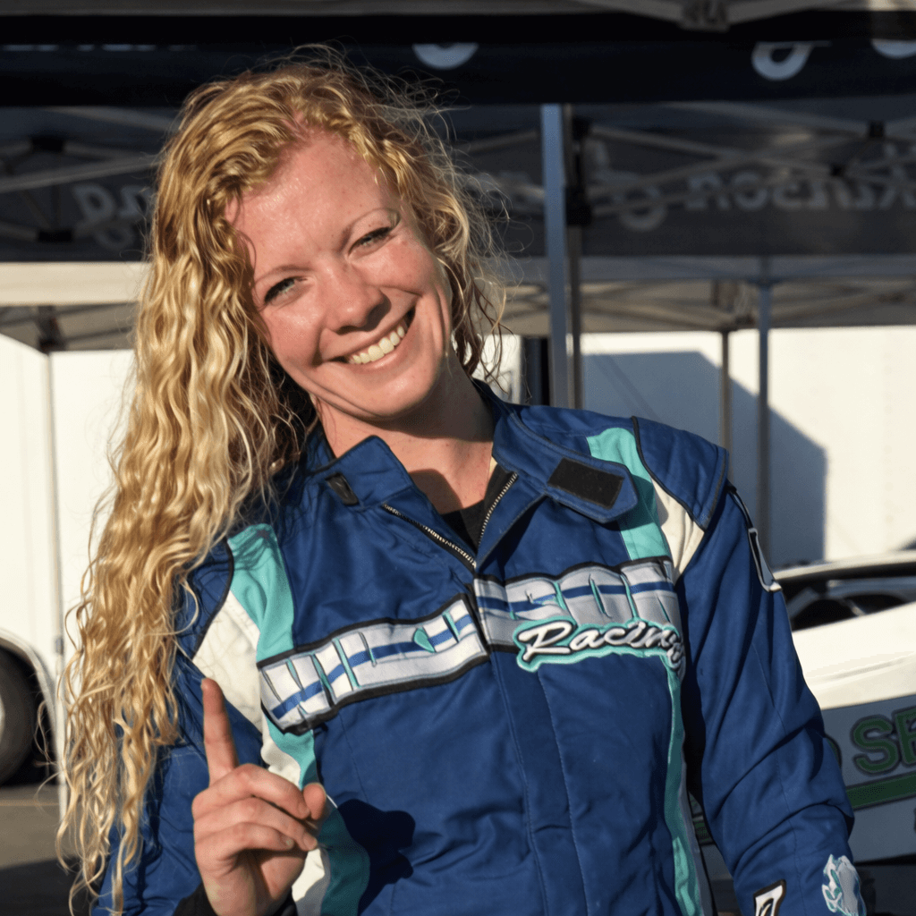 Haylie Wilkinson posing in front of her race car holding up a number 1